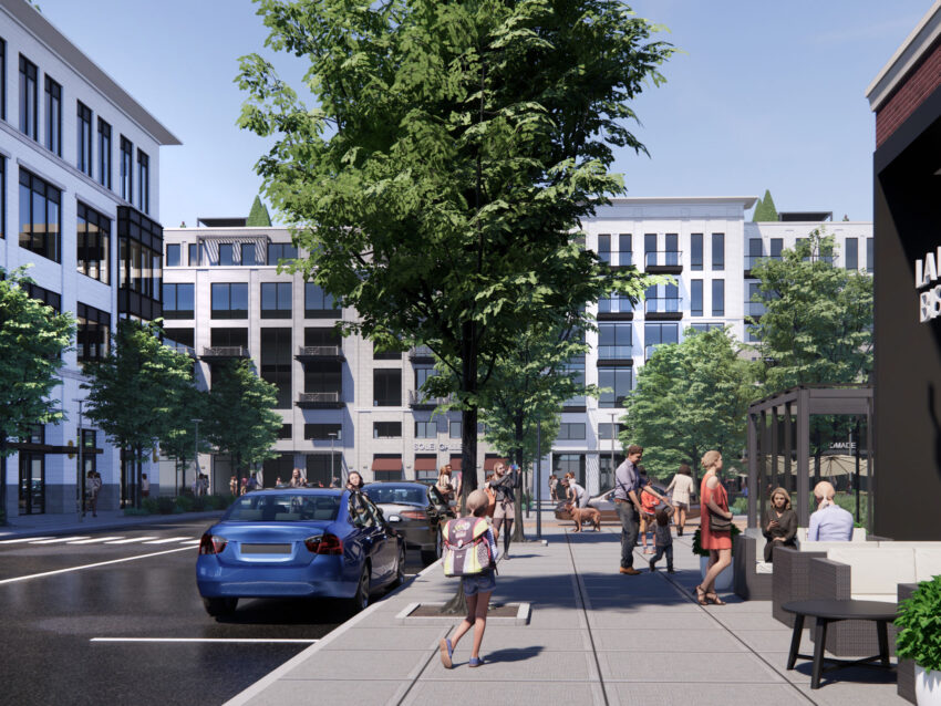 Large bustling sidewalk next to a street with parked cars and white building in the background